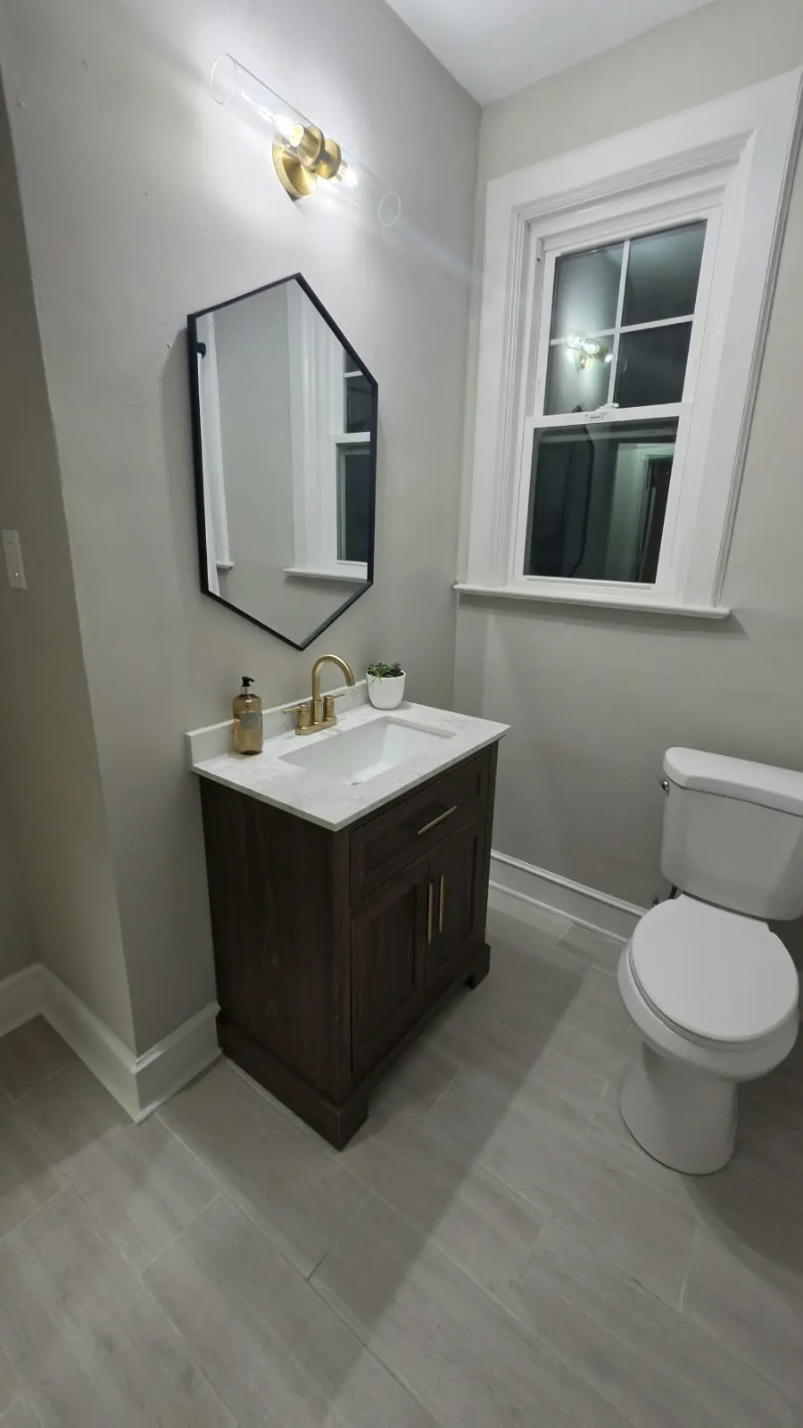 Bathroom vanity with a hexagon mirror and brass fixtures in Hampton, VA