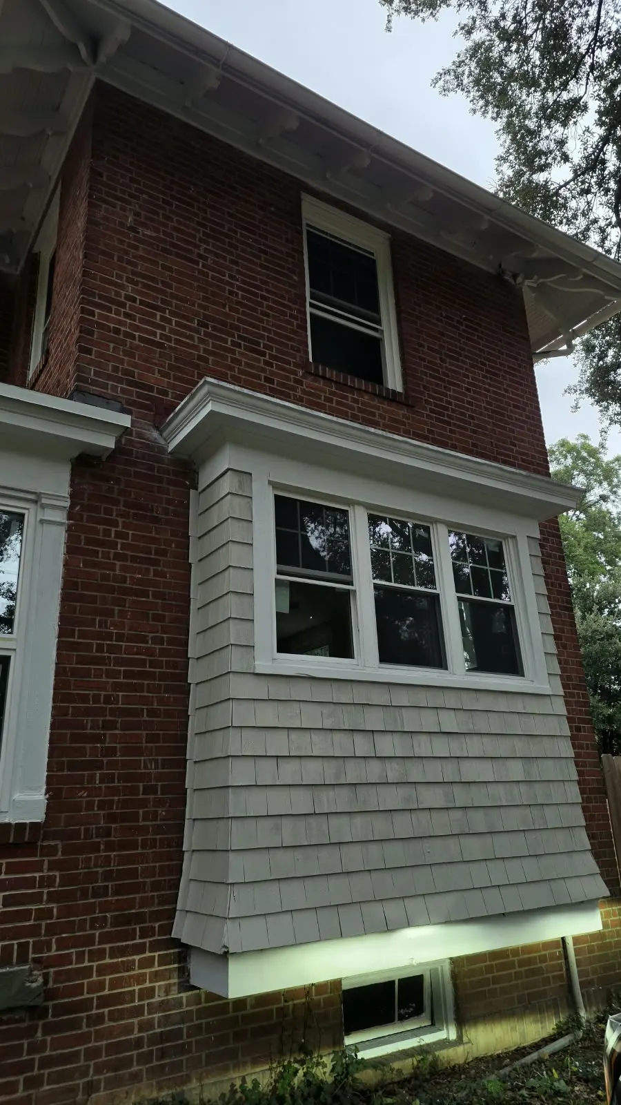 Shingle-style siding on a bay window of a brick home in Hampton, VA