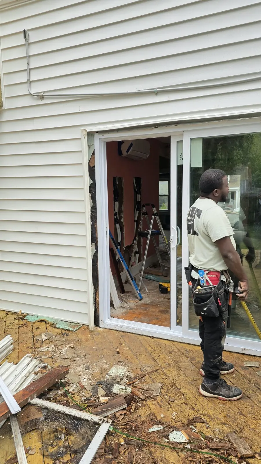 Crew member at a sliding door opening framed in vinyl siding in Hampton, VA