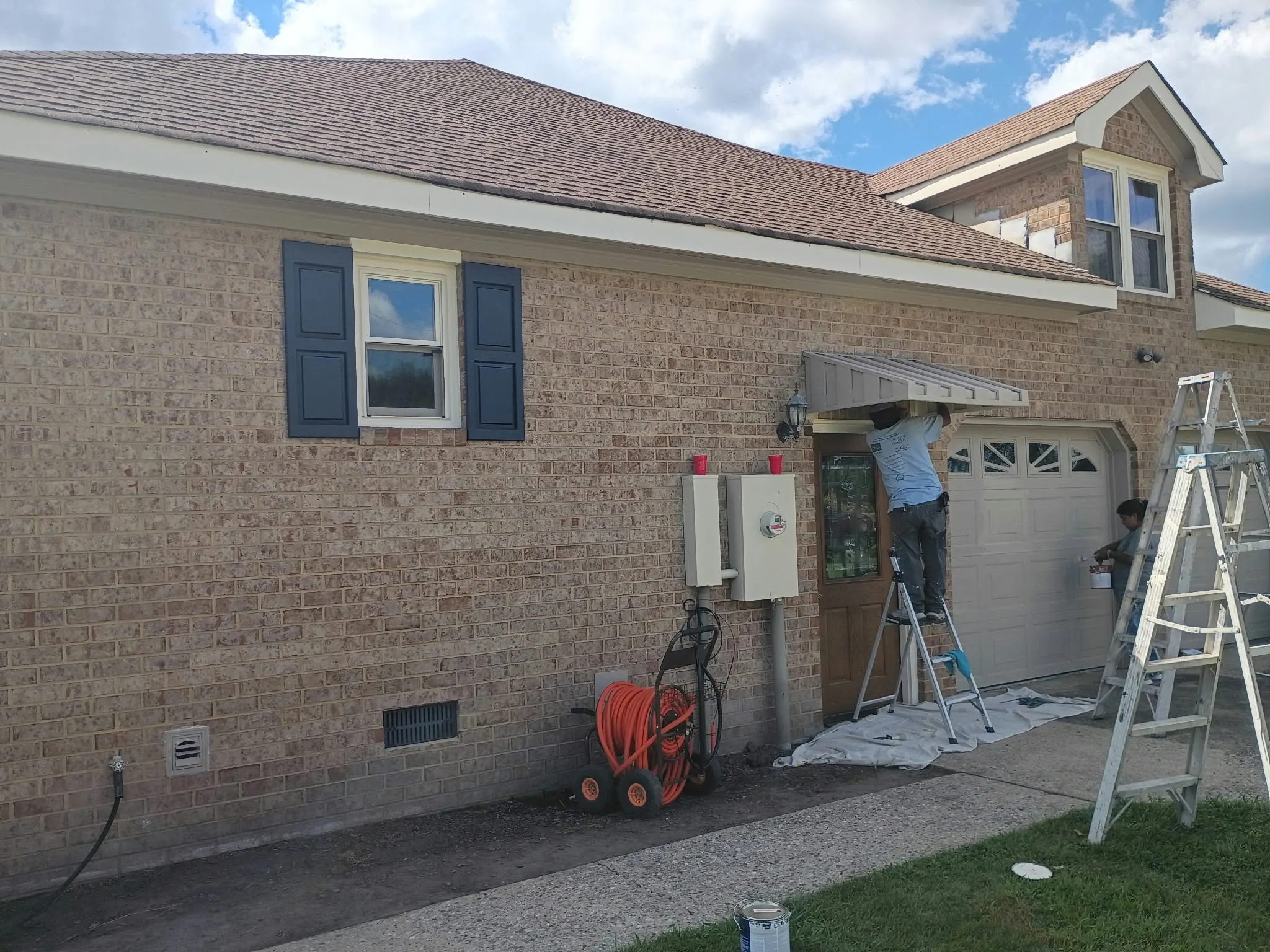 Crew member on a ladder doing exterior trim work on a brick home in Hampton, VA
