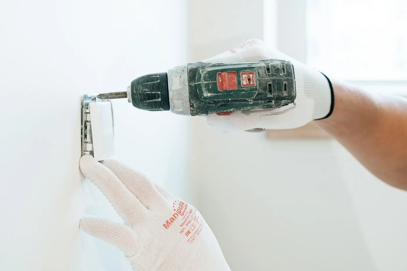 Hands installing a wall outlet with a drill, electrical work in Hampton, VA
